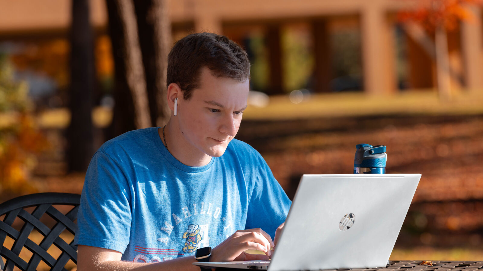 A male history major at UT Tyler studies on a laptop outdoors.