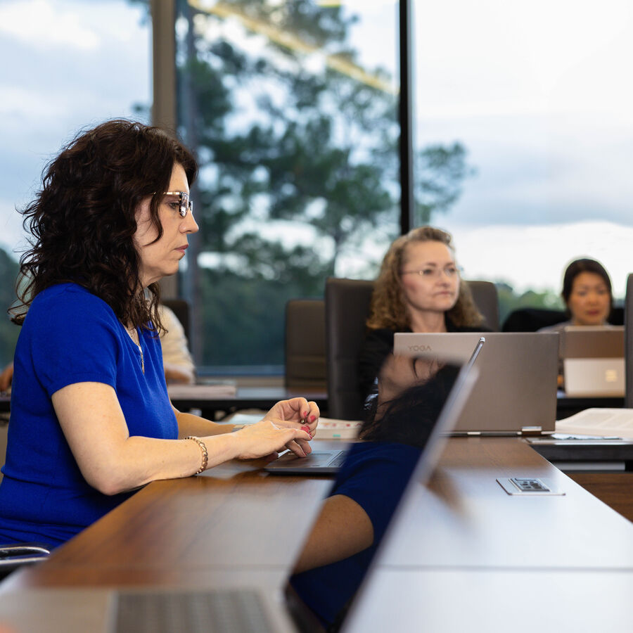 Adult students sit in a classroom with laptops for 's Executive MBA in Healthcare Management at 