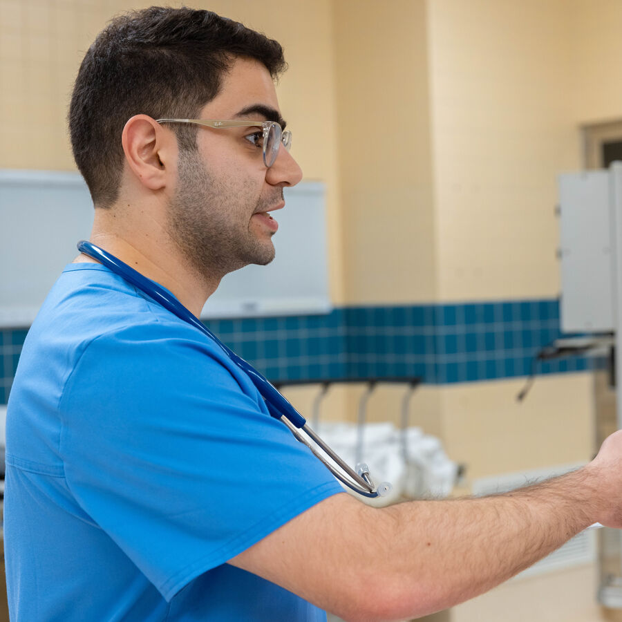 A male School of Medicine student in scrubs wears a stethoscope during SMILE (simulation lab on north campus), a collaborative health professions event at UT Tyler