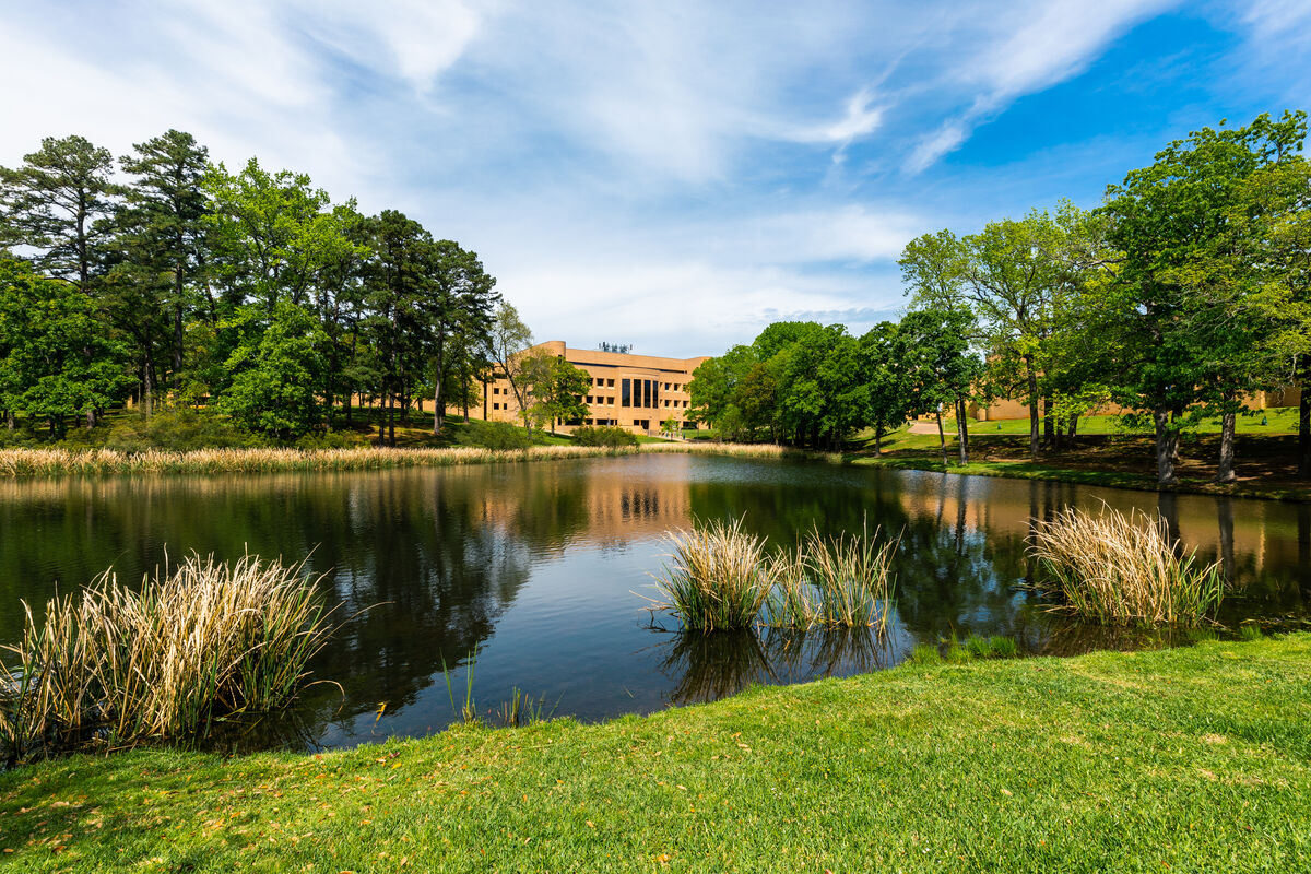 A wide shot of the campus lake, the Ratliff south building is seen on the other side of the lake