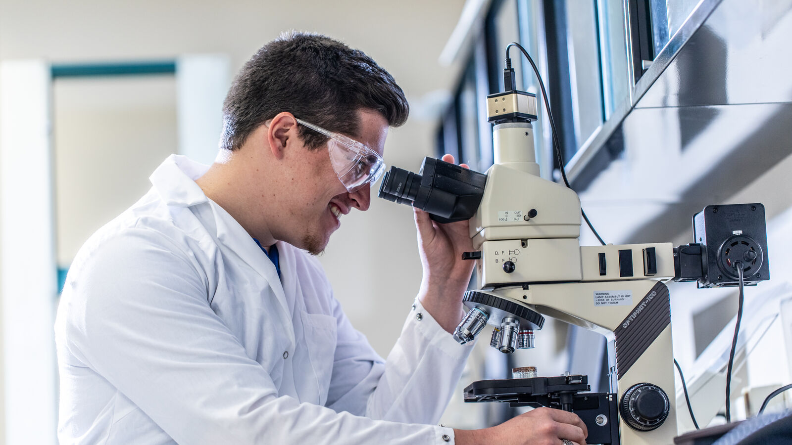A male student uses a microscope in a research lab at UT Tyler