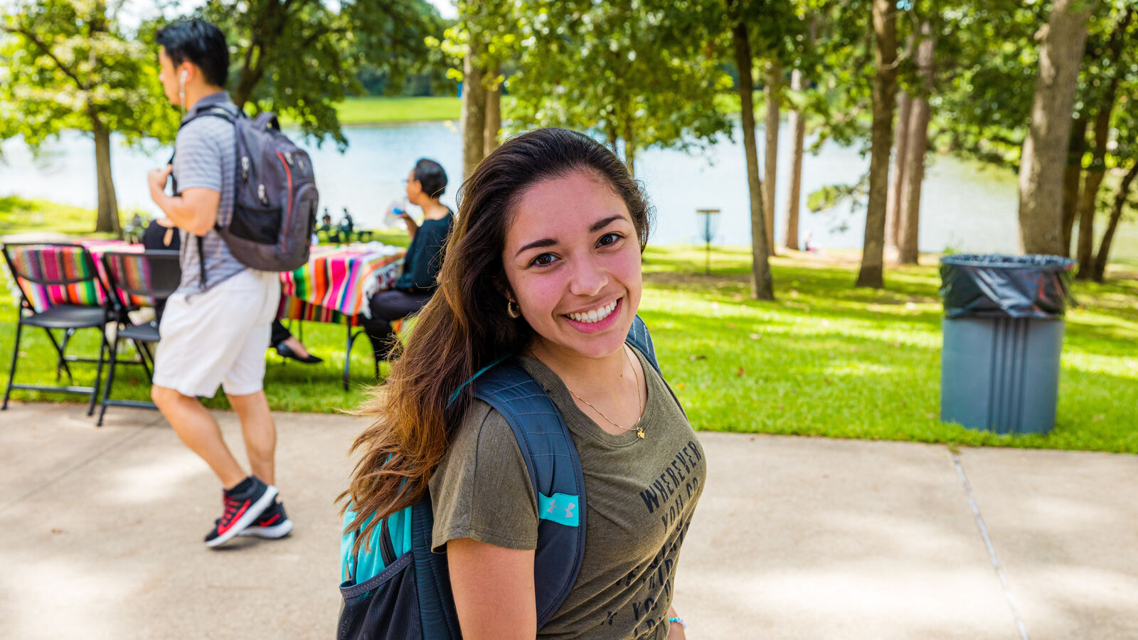 A smiling female student walking outdoors on The University of Texas at Tyler's main campus
