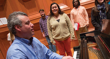 Faculty member with students at choral practice