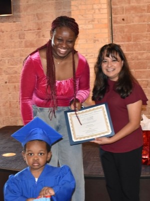 Nurse-Family Partnership program graduates, Latifah Opeodu and her son, receive their certificate from Ivette Miles, the NFP nurse supervisor. Beyond clinical care, NFP focuses on empowering mothers to achieve their educational and career goals, connecting mothers to critical resources such as childcare and flexible education options.