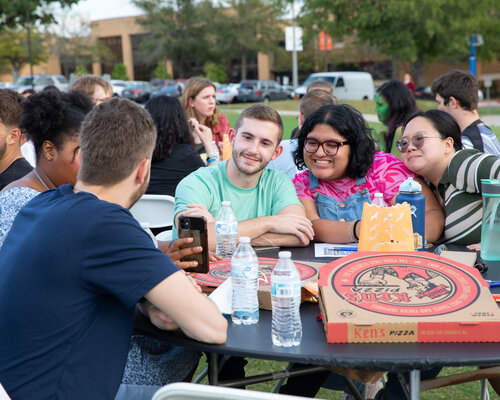 Students sitting around an outdoor table at a quiz night event
