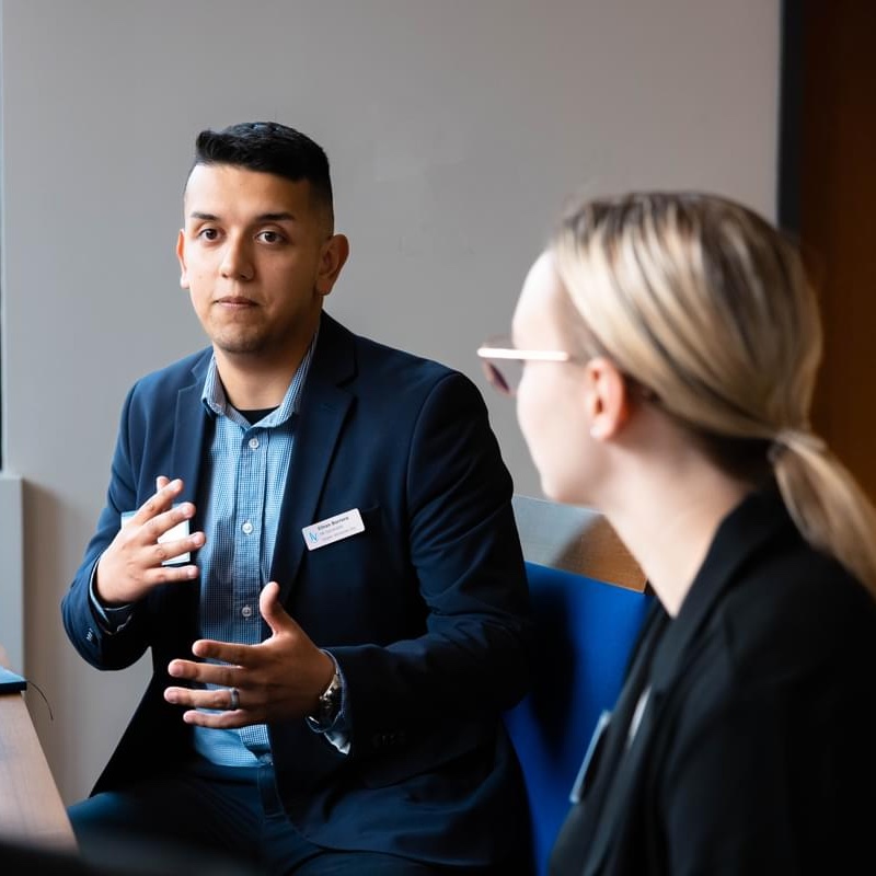 A male UT Tyler student speaking at a table