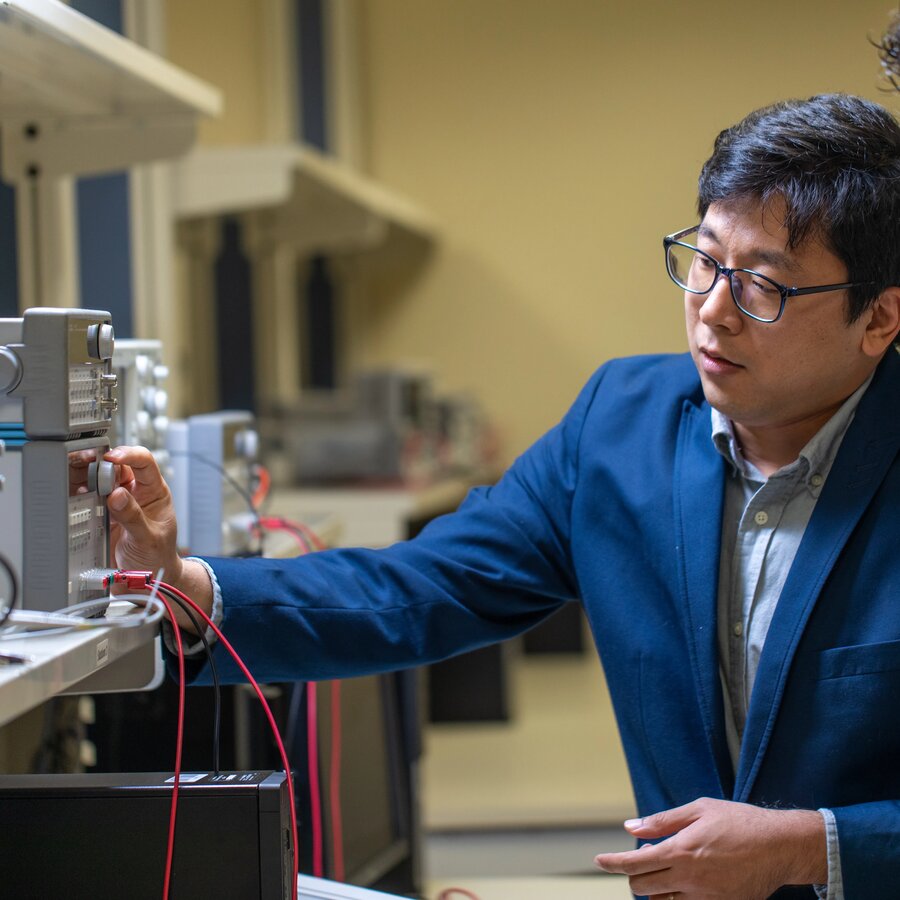 A professor interacting with an electric engineering project