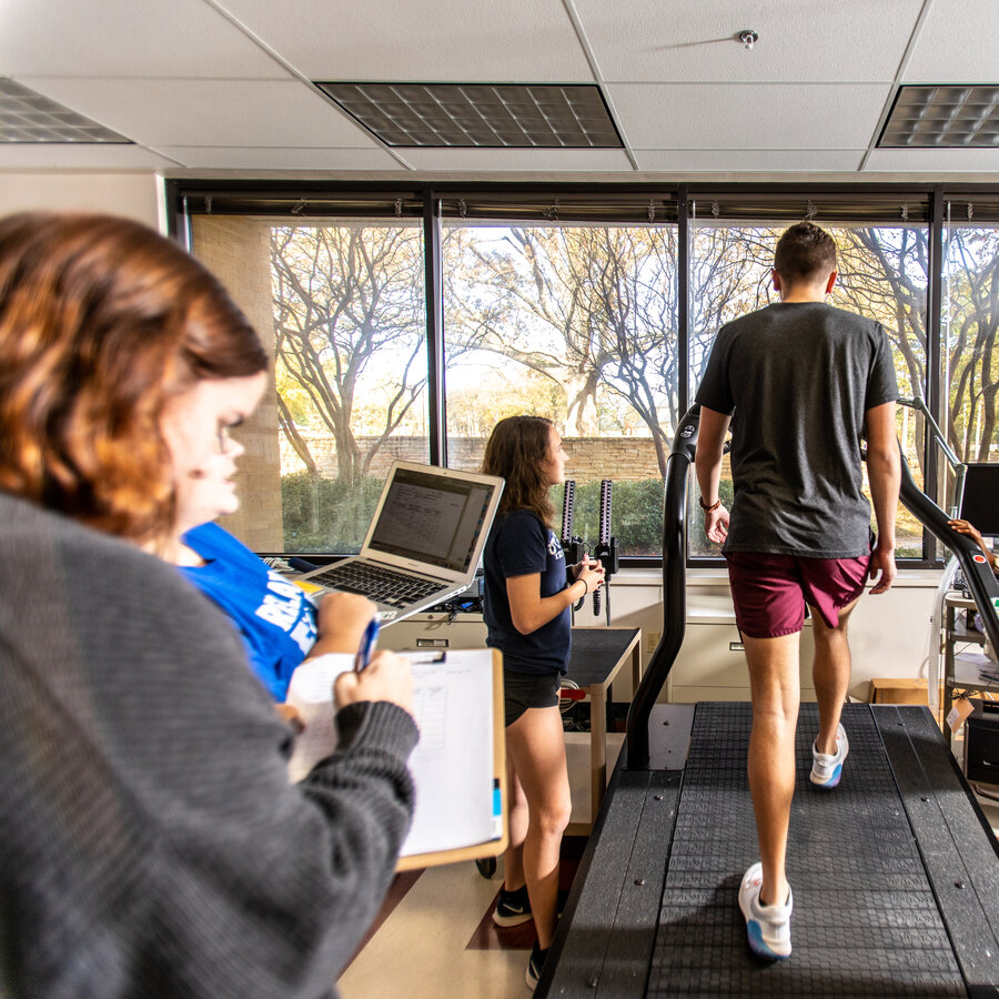 Person on a treadmill while students are taking notes