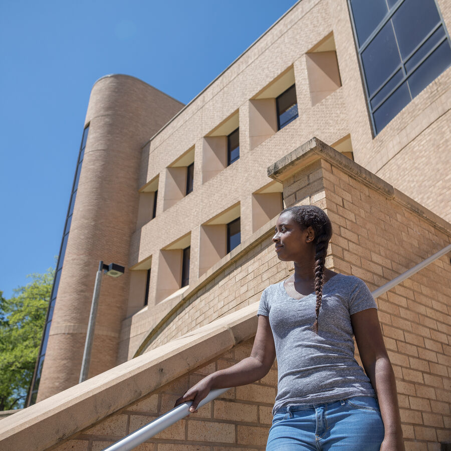 Female UT Tyler student standing on the steps to a building on campus