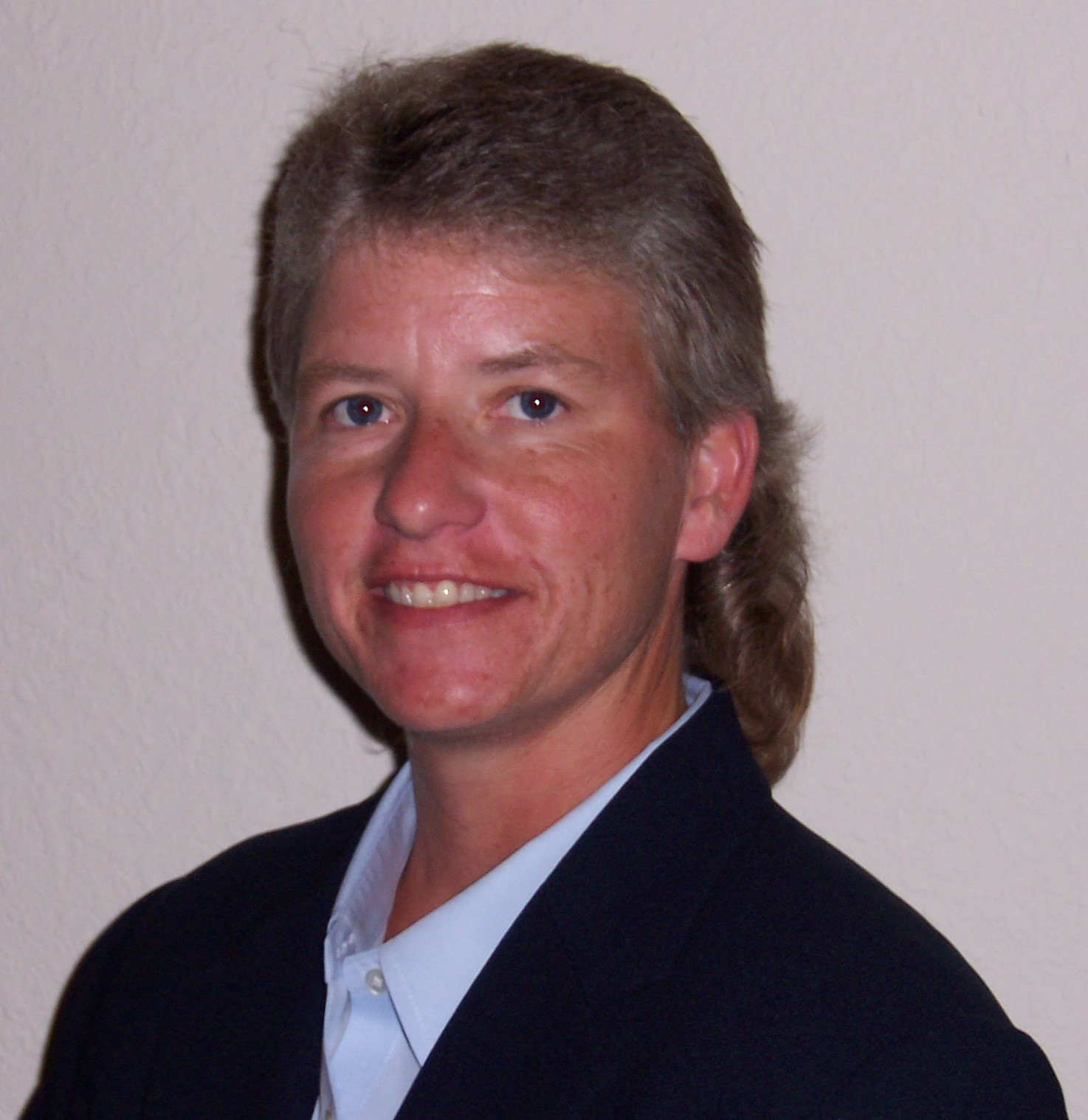 Kelly Moore An MS in Human Resource Development student at UT Tyler wearing a suit and standing next to a table