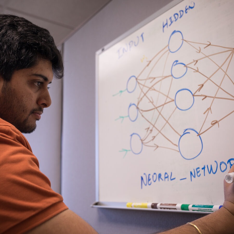 Student writing on a white board information about neural networks