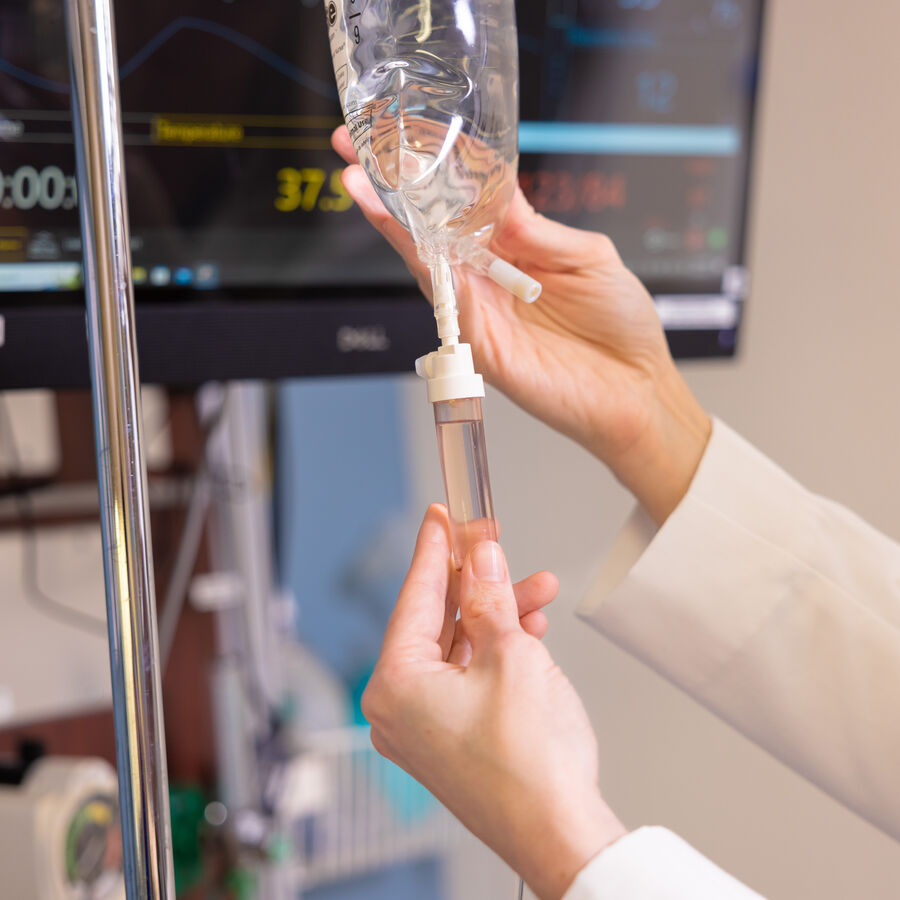 A close up of a nurse's hands adjusting an IV drip.