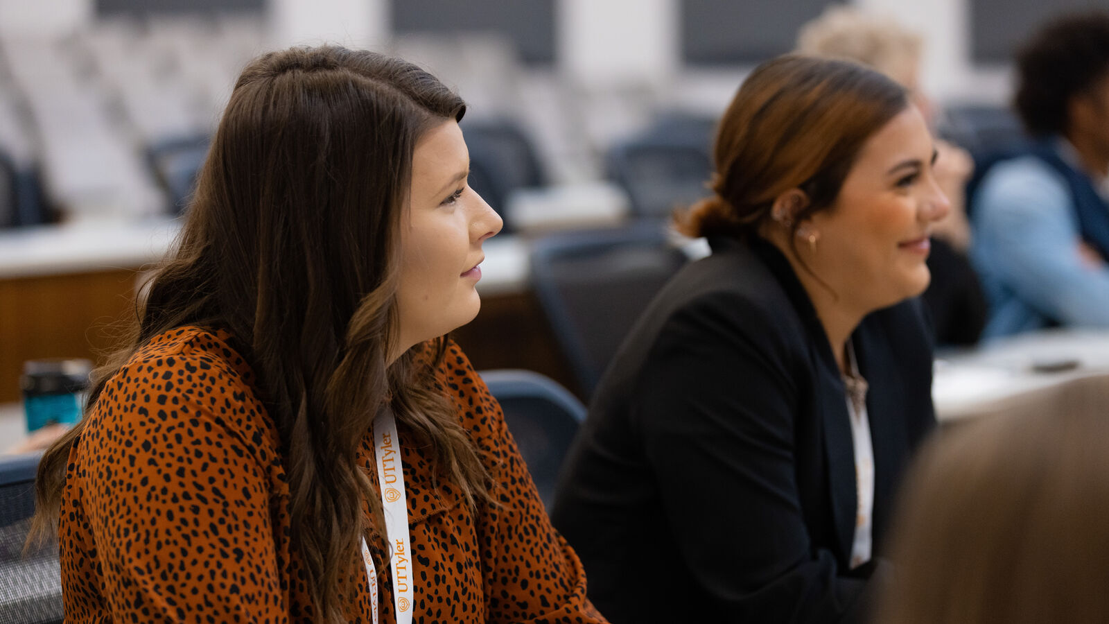 Two female UT Tyler students listening to a presentation in a classroom