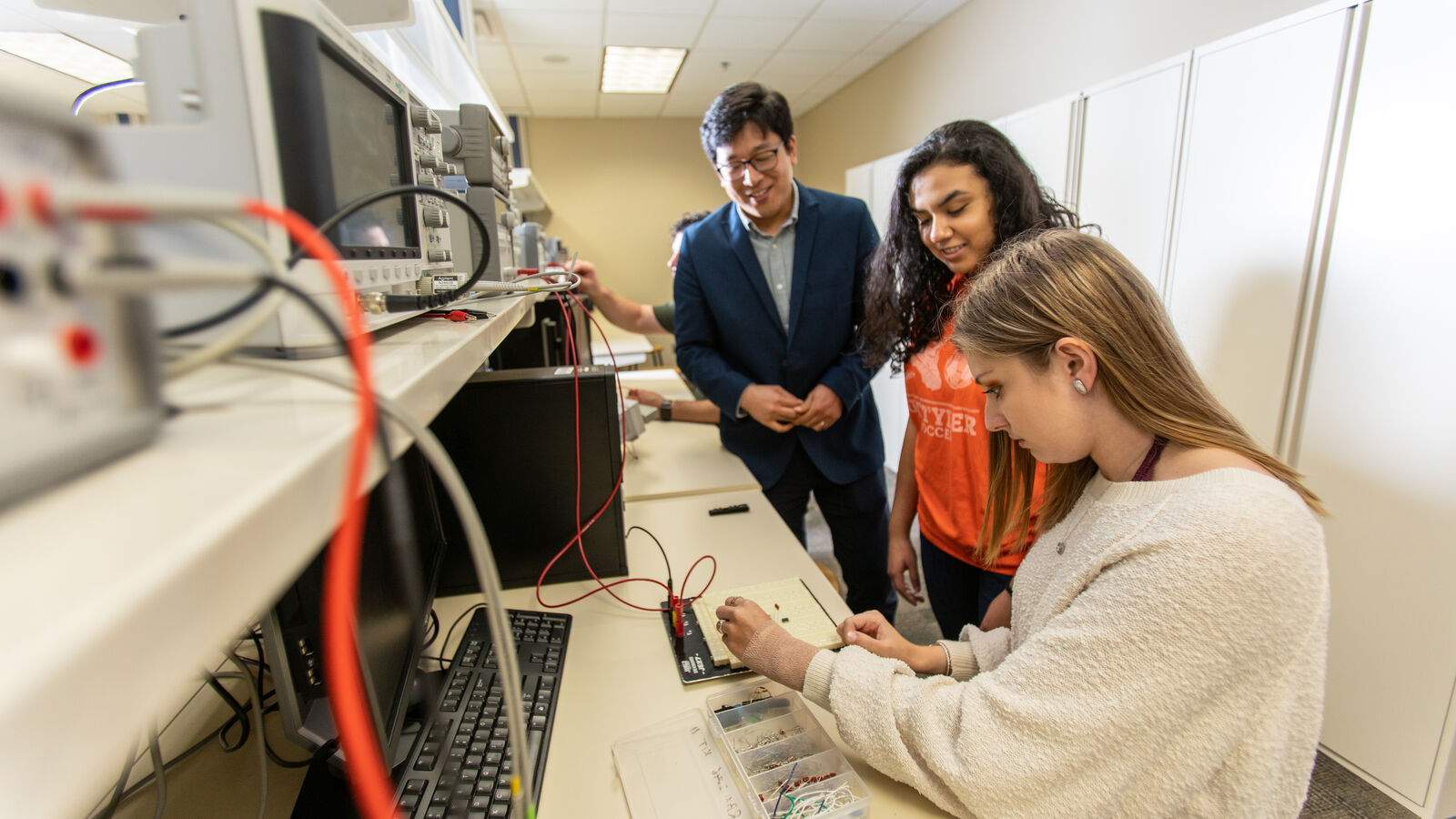 Professor and computer engineering students interact on an electric engineering project
