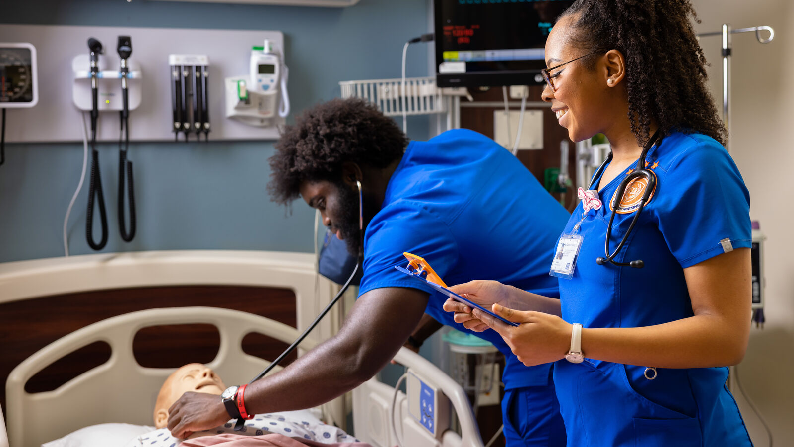 Two BSN students at UT Tyler practice taking patient vitals on a dummy in a simulation environment