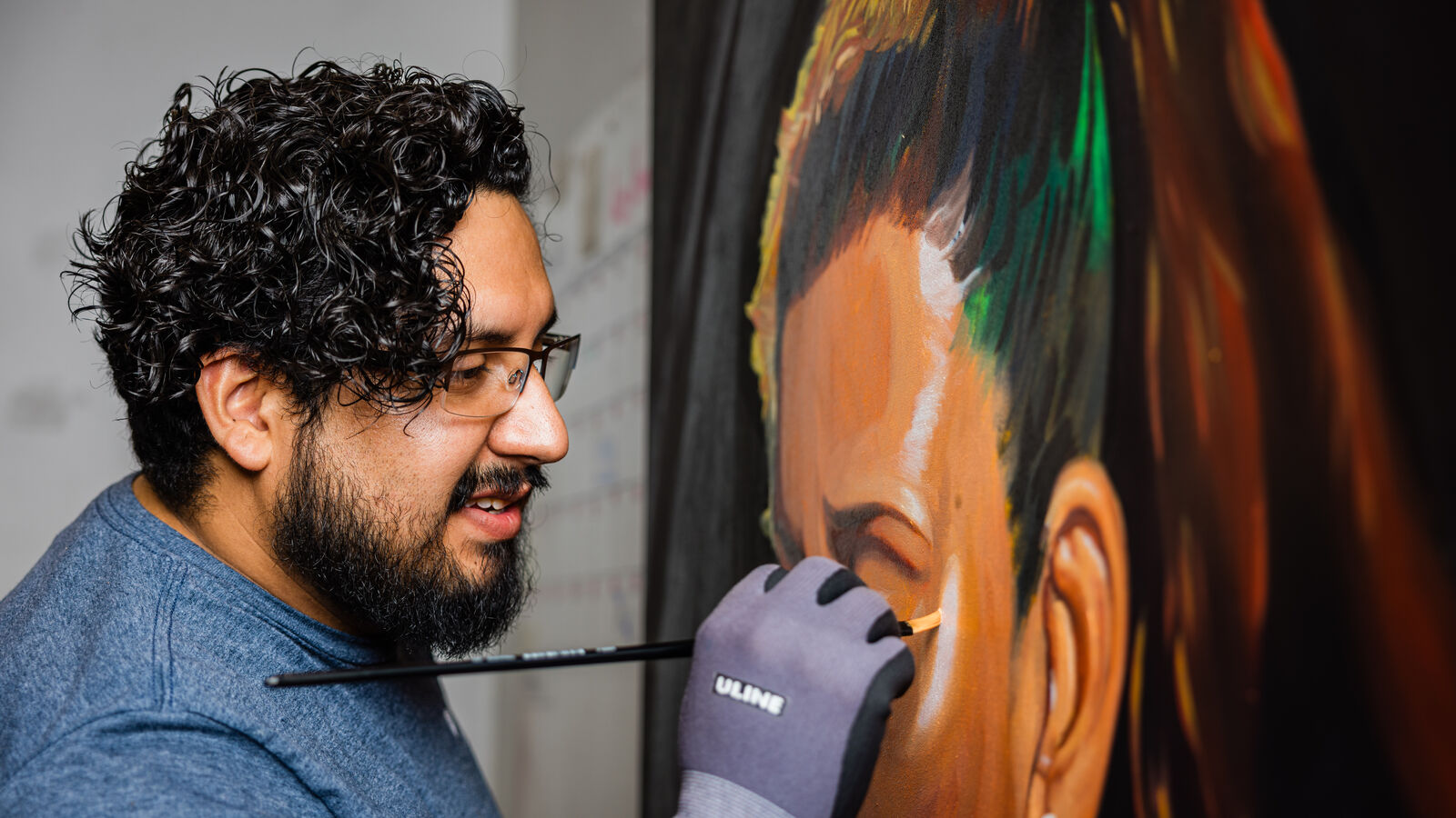 A male MA in Art student working on a painting in UT Tyler's Art Department
