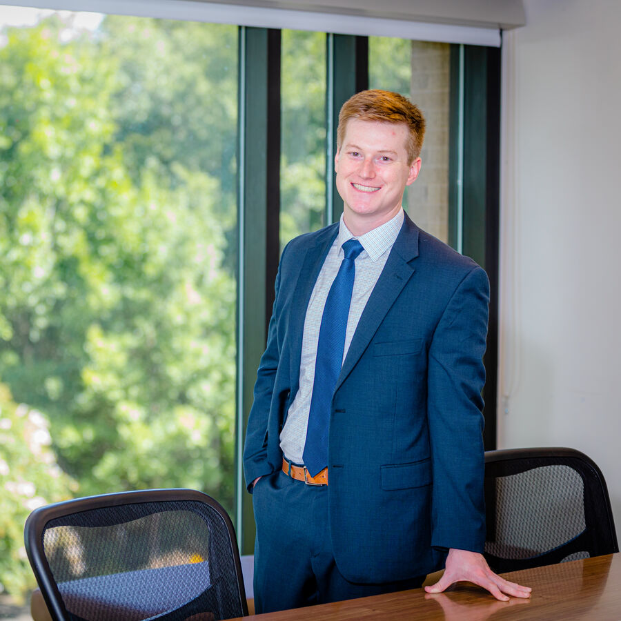 An MS in Human Resource Development student at UT Tyler wearing a suit and standing next to a table 