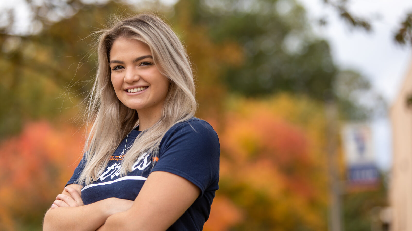 A female student stands outdoors in fall on The University of Texas at Tyler campus