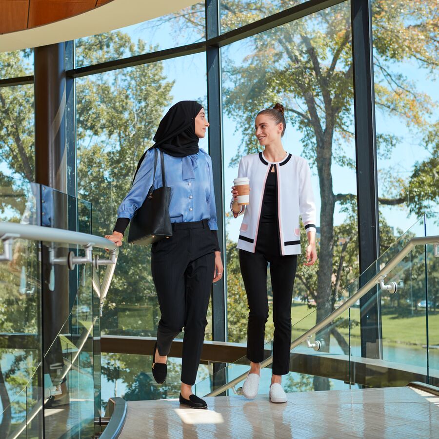 Two female students talk while walking through The University of Texas at Tyler's Fisch College of Pharmacy