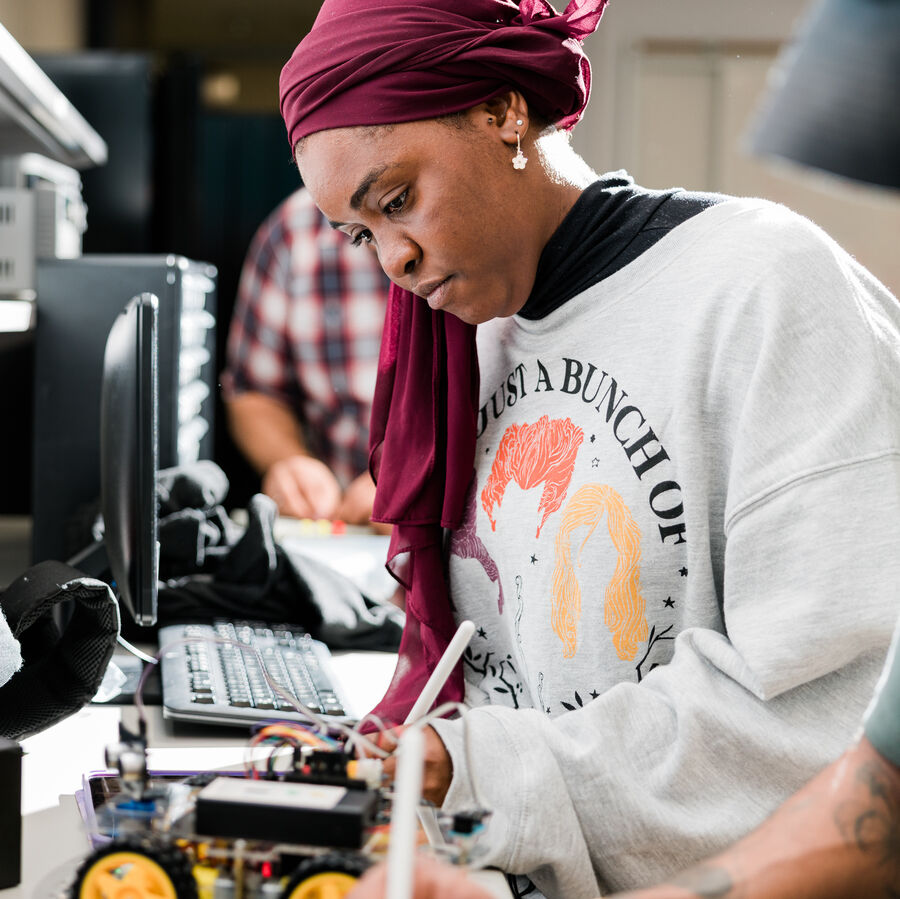 A female student works on the electrical components of a model car at UT Tyler's Houston Engineering Center