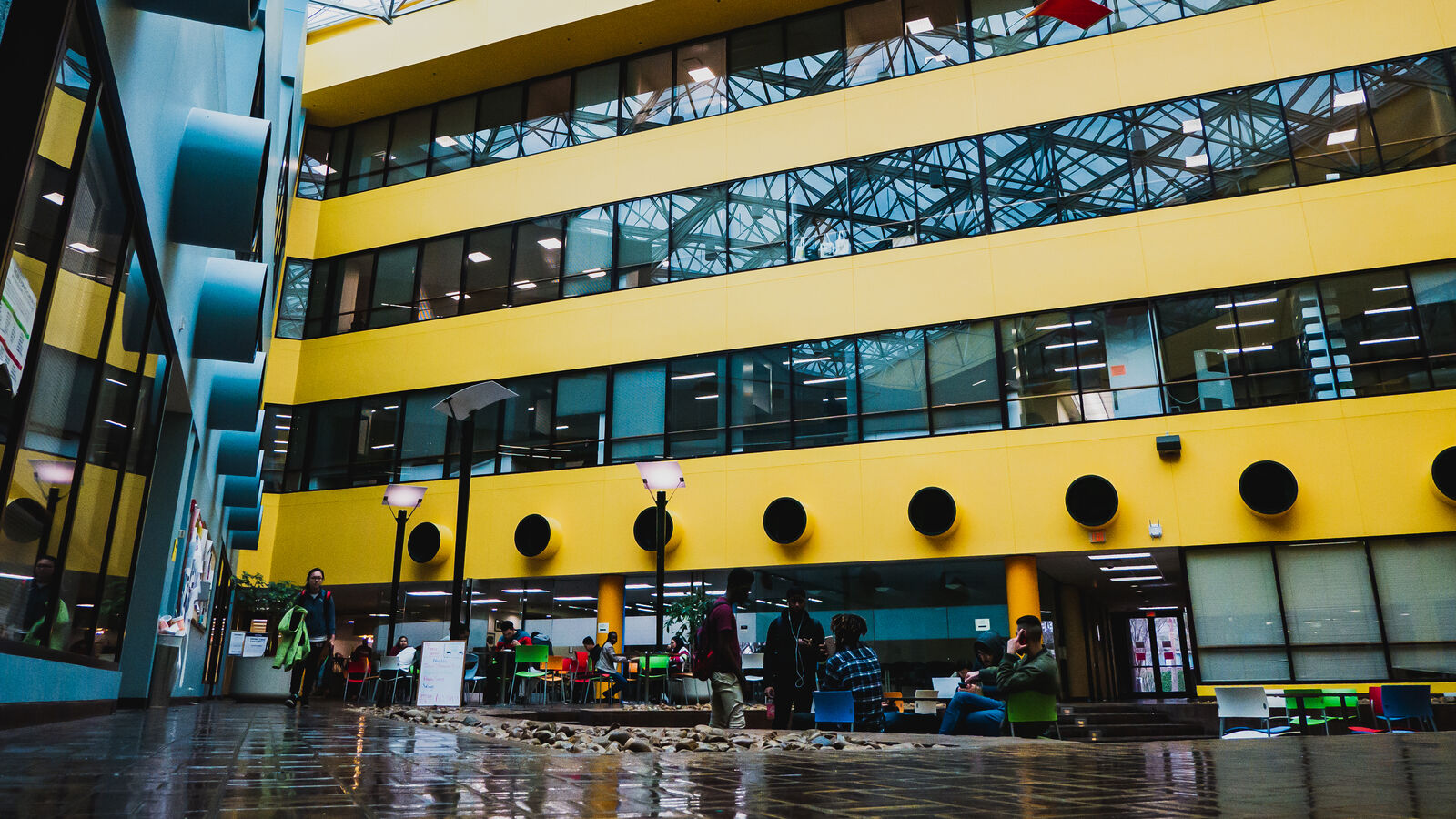 This image shows the Houston Engineering Center: a blue and yellow building with large glass windows and a glass ceiling.