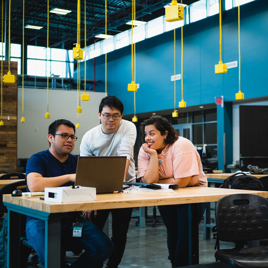 Two students look on while one person works on a laptop at UT Tyler's Houston Engineering Center