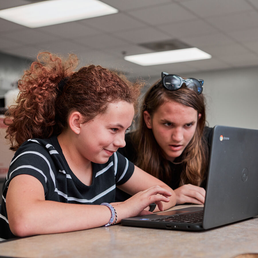 An elementary school student and a high school student work together at a laptop at UT Tyler's Longview University Center