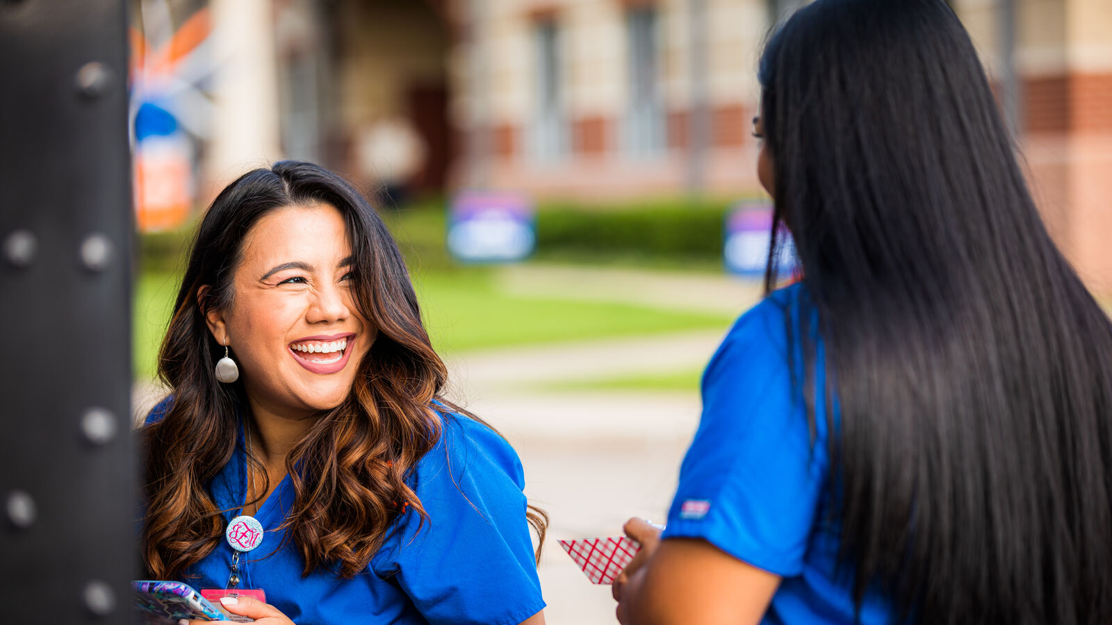 Nursing students in blue scrubs talk and laugh outside of Longview University Center.