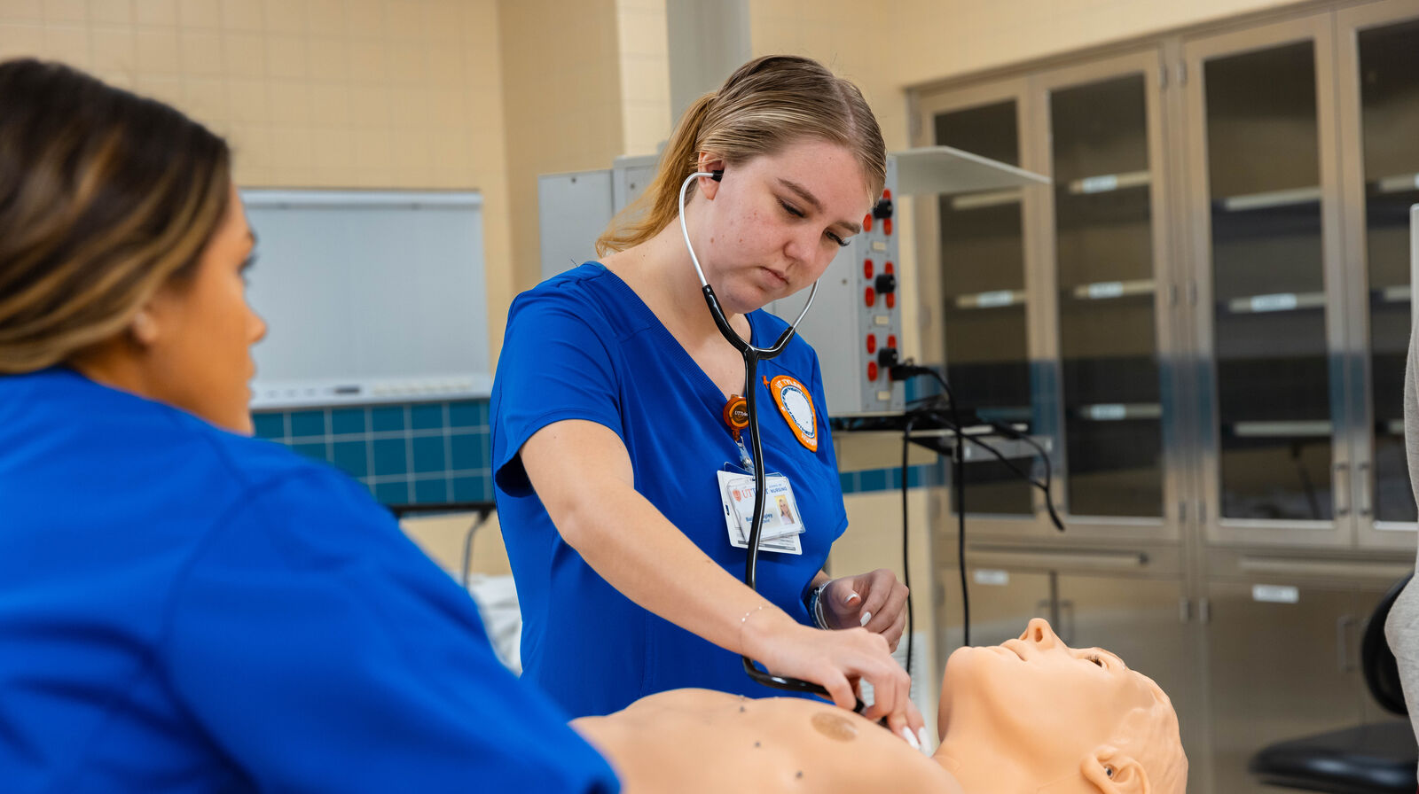 Two UT Tyler School of Health Professions students practice taking patient vitals in a simulated environment