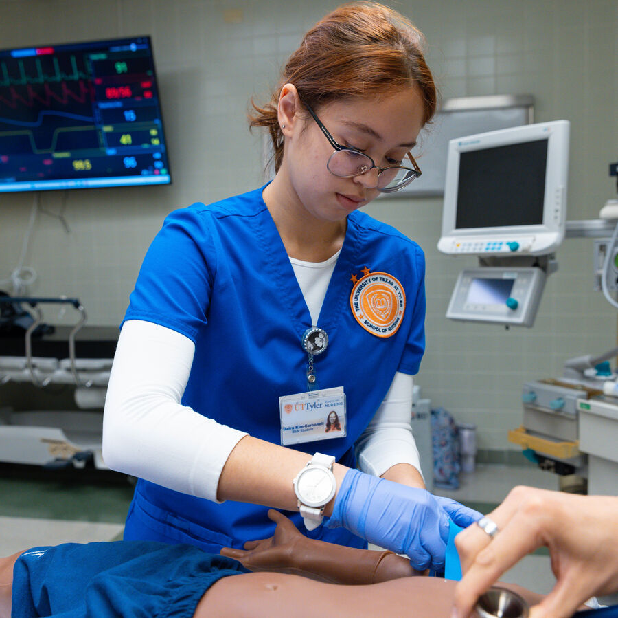 A UT Tyler School of Health Professions undergraduate student practices monitoring a patient in a simulated space