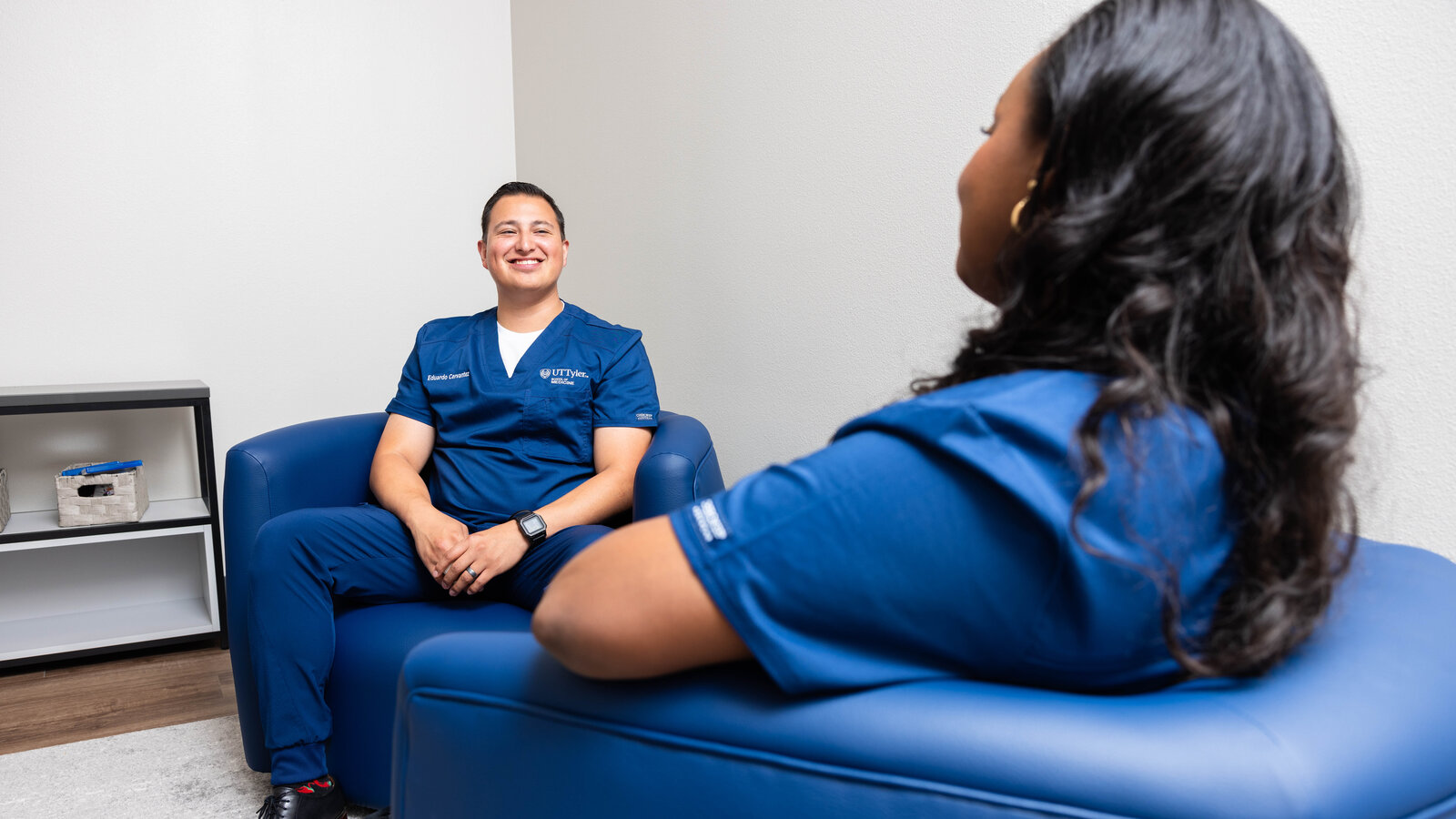 Two medical students sitting in chairs talking and smiling.