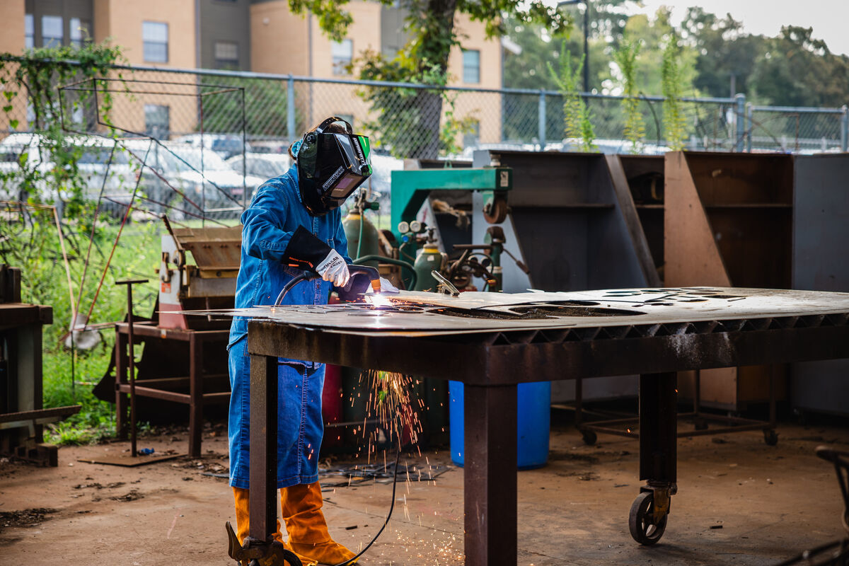 An art student using a plasma cutter on metal sheets