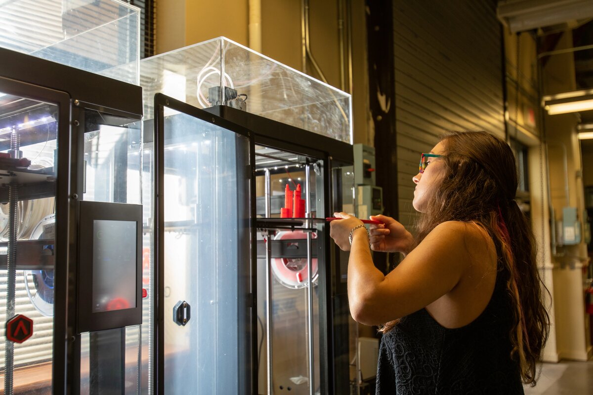 A civil engineering student taking a building sculpture out of a 3D printer