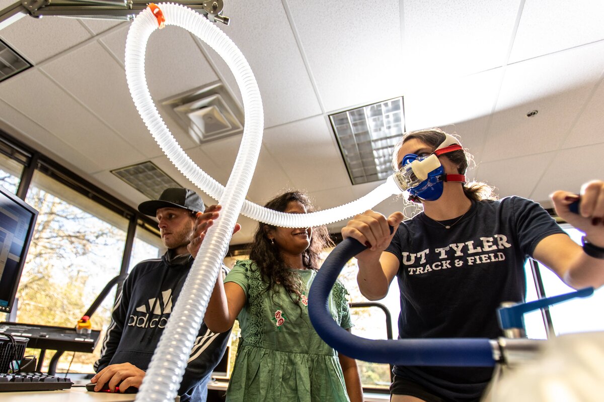 Kinesiology students taking vitals of a student on a stationary bike