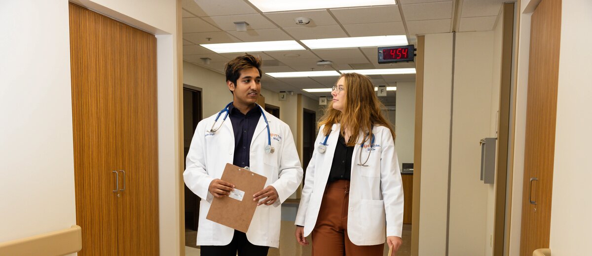 Two medicinal students are walking down the hall of a hospital.