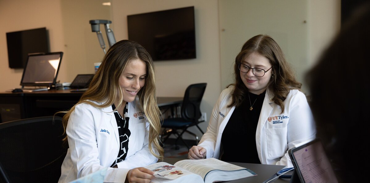 A pair of medicine students are gathered around an open book