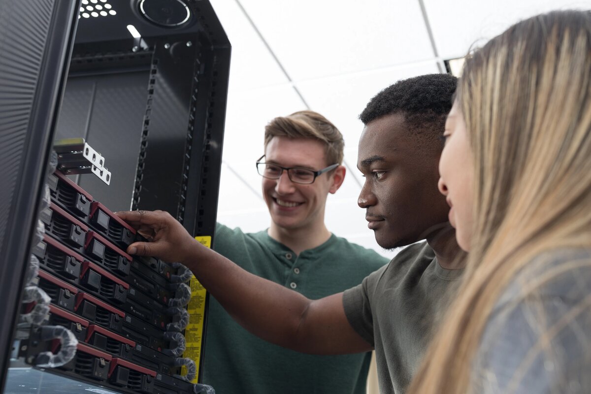 three IT students around a server configuring drives