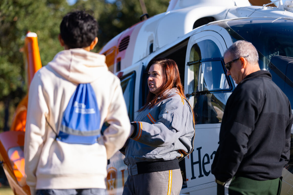 Students and Faculty stand outdoors near a Helicopter during the Pre-Health Student Conference.