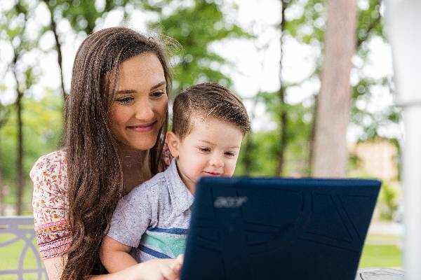 Student-mother with child in front of a laptop on campus