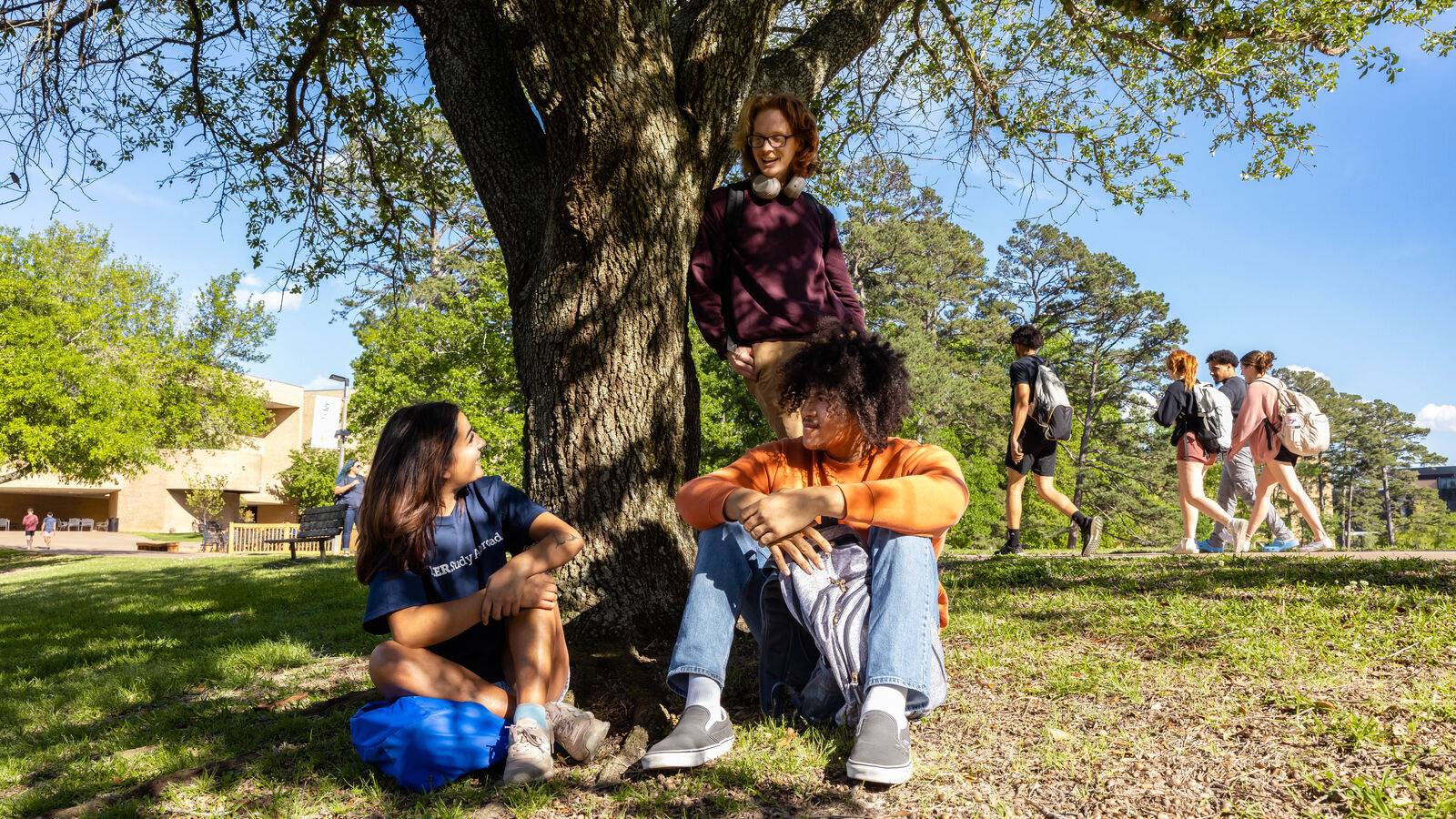 Two University of Texas at Tyler students sit beneath a tree on the main campus