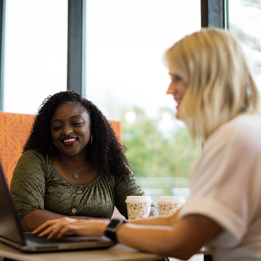 Two female staff members at The University of Texas at Tyler sit in front of a computer