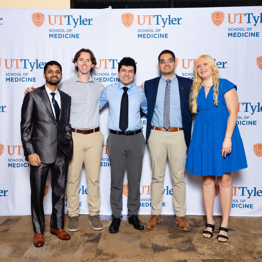 Five individuals standing in front of a UT Tyler School of Medicine backdrop.