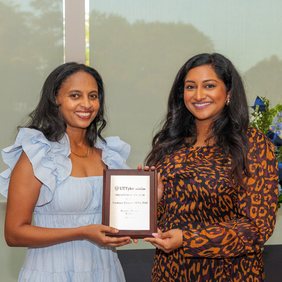 Two women smiling and holding an award plaque.
