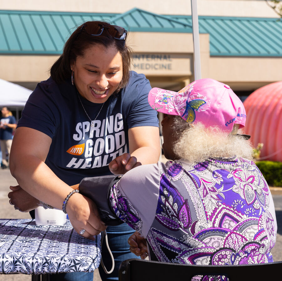 A woman takes an older person's blood pressure at a health fair