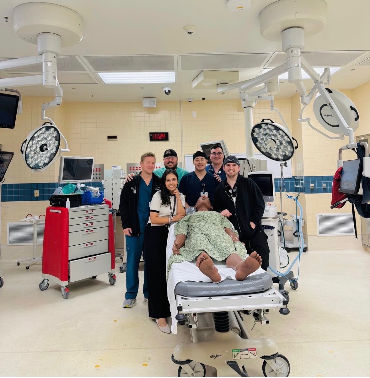 Group of anesthesia residents in an operating room with a simulated patient on a hospital bed.