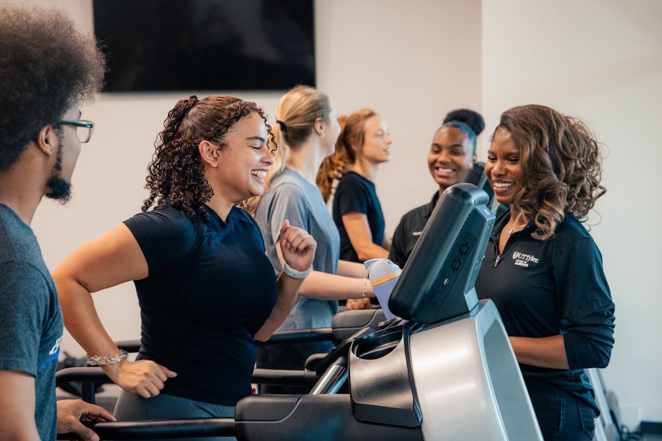 Students smiling and using the treadmills