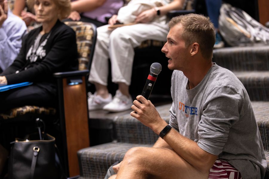 Adult male sitting down on stairs holding a microphone