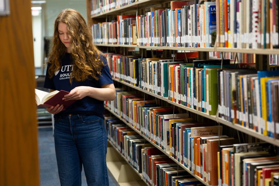 Person holding a book between stacks in a library
