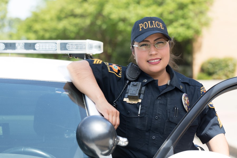 Police officer standing with an elbow on top of a police car